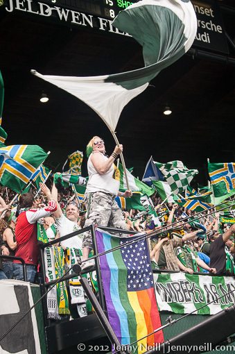 Sunday White waving her support of the Timbers above her rainbow flag